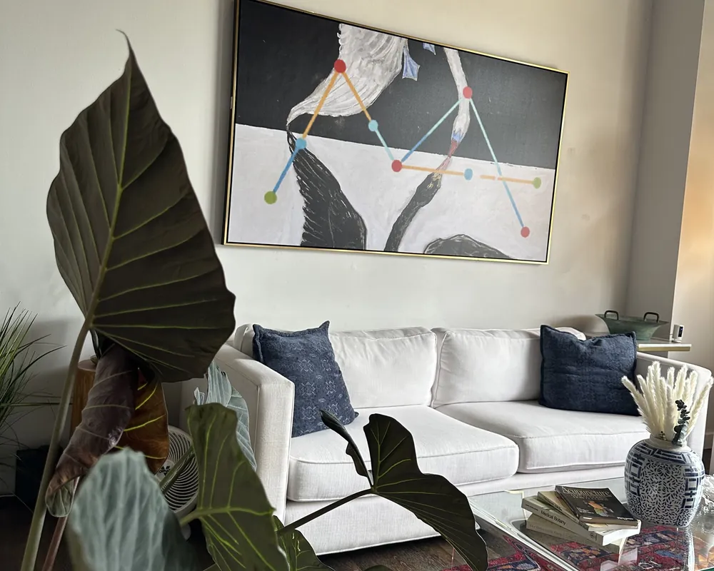 The lobby at the Brentwood clinic, with a white sofa, large plants, a patterned rug, and framed crane artwork