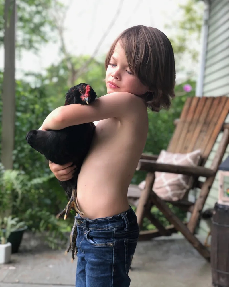 The Poffenbergers' son holding a black hen on a back porch in Middle Tennessee