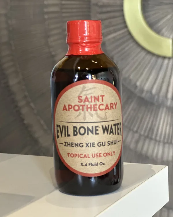 A bottle of Saint Apothecary Evil Bone Water liniment, labeled for topical use only