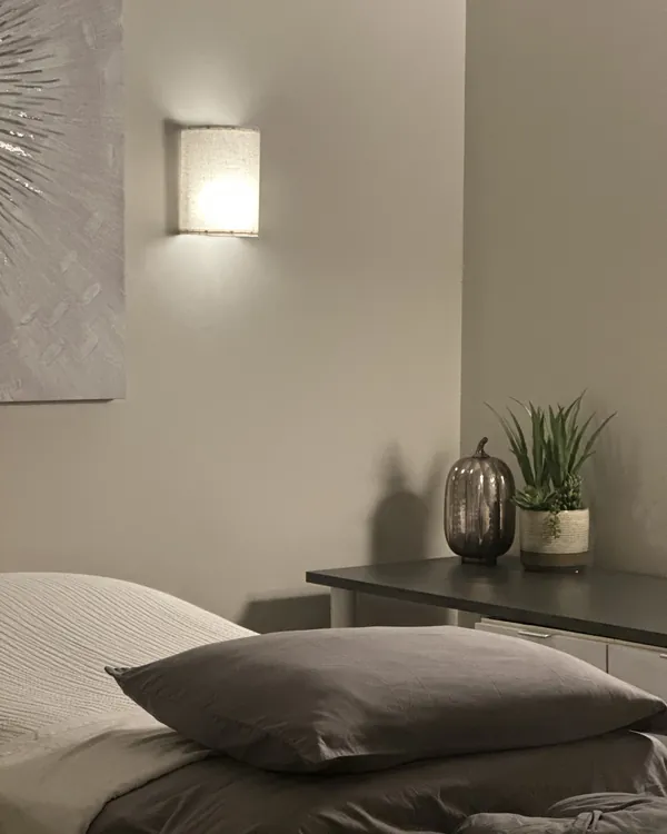 A treatment table, wall sconce, and potted plant in an individual treatment suite at the Brentwood clinic