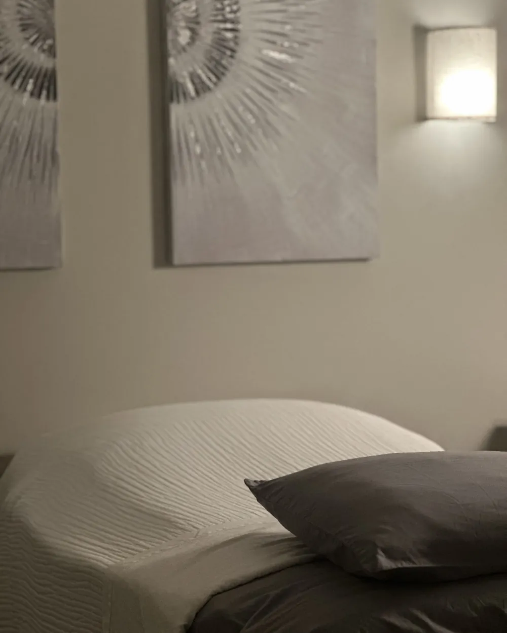 An individual treatment suite at the Brentwood clinic, with a made treatment table, wall sconce, and framed art